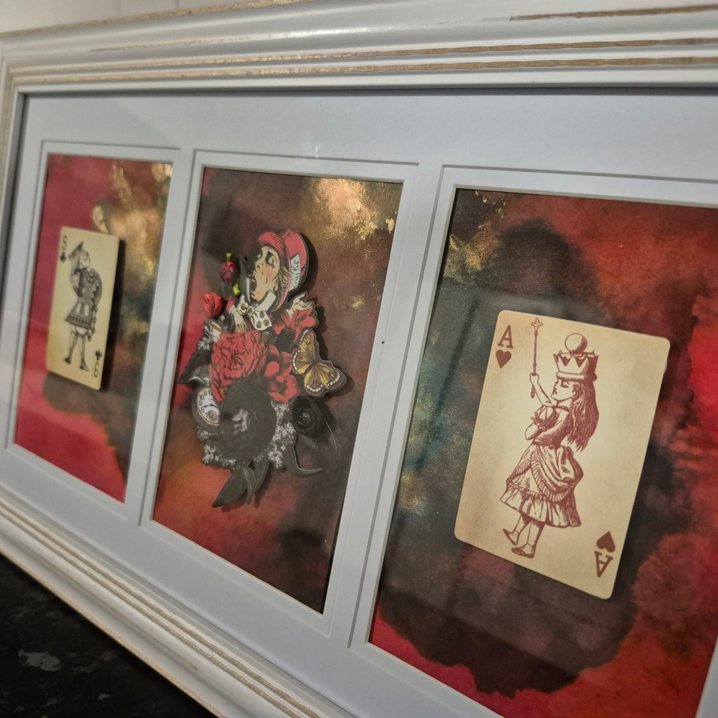 Three framed pieces of art featuring playing cards and decorative elements, characters from Alice in Wonderland