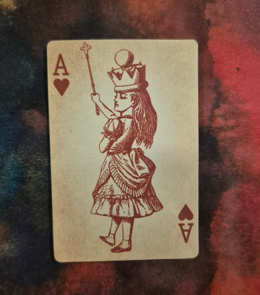 Playing card with Alice in Wonderland design on a textured surface