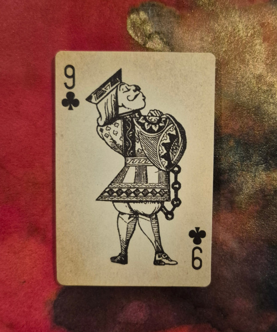 Playing card with a black and white design on a textured red and gold background