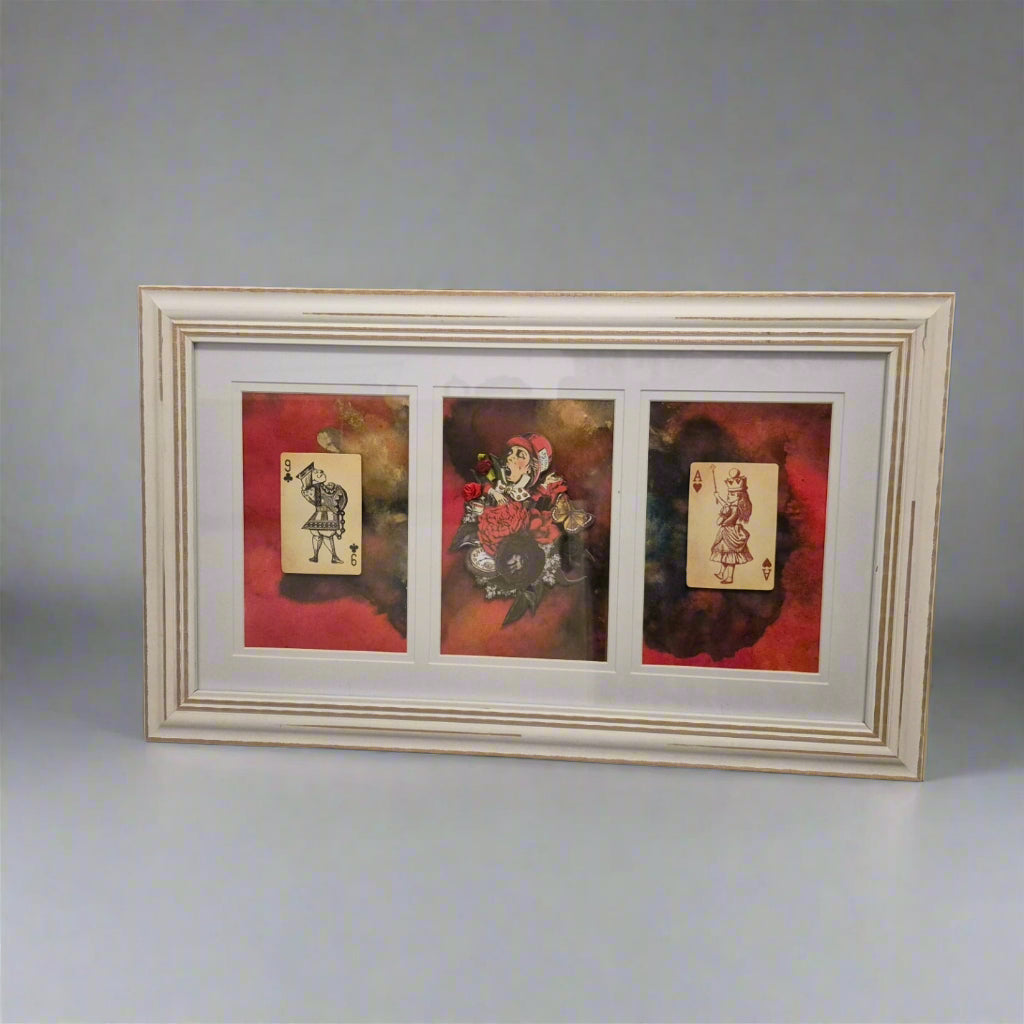Framed artwork with three card-like images on a floral-patterned surface.