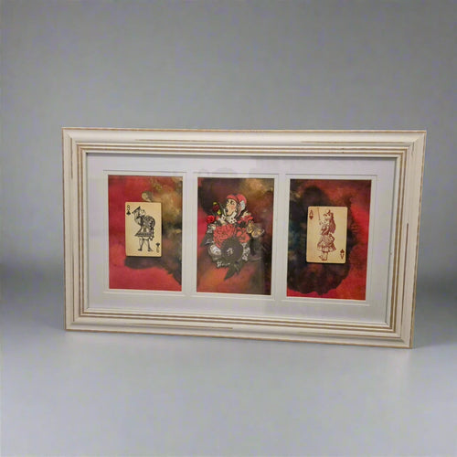 Framed artwork with three card-like images on a floral-patterned surface.
